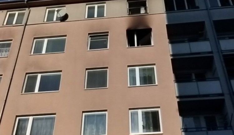 Požár v paneláku na Na Černé cestě. Hasiči z hořícího bytu zachránili vážně zraněného muže, letěl pro něj vrtulník