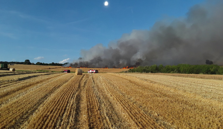 Čtrnáct jednotek hasičů bojuje s požárem na poli u Hranic. Situaci komplikuje silný vítr