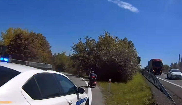 Hlídka celní správy doprovází seniora na elektrickém vozíku z dálnice D35