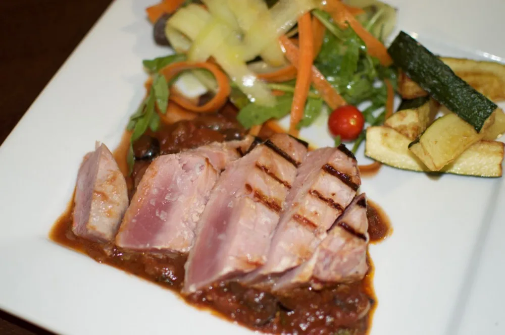 Grilovaný steak z čerstvého tuňáka s červeným vínem, kapari a olivovou omáčkou, cuketové hranolky a svěží míchaný salát