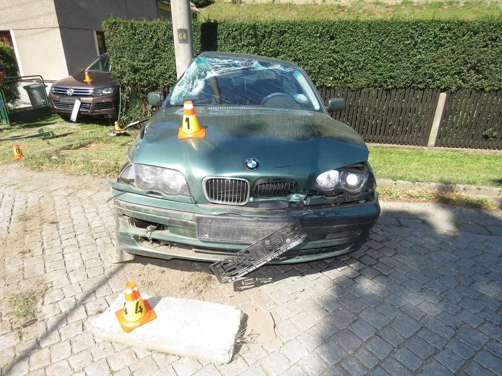 Řidič dostal smyk. Naboural zaparkované auto, plot domu a sloup vysokého napětí