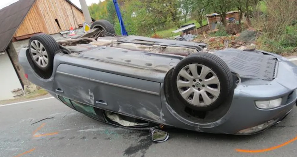Řidička narazila se svým Superbem do kamenné zídky, urvala kolo a auto přetočila na střechu