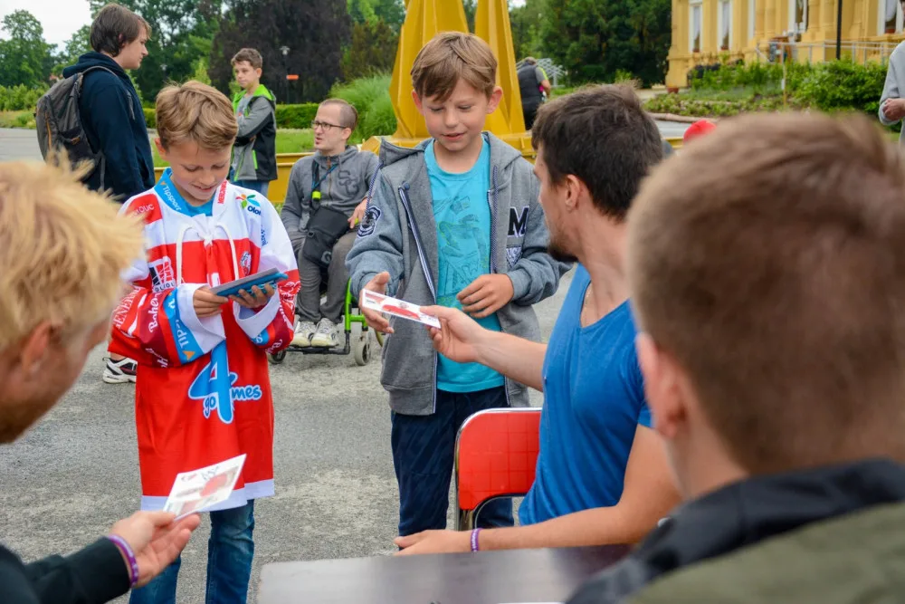Petr Strapáč (v modrém) předává podepsané kartičky