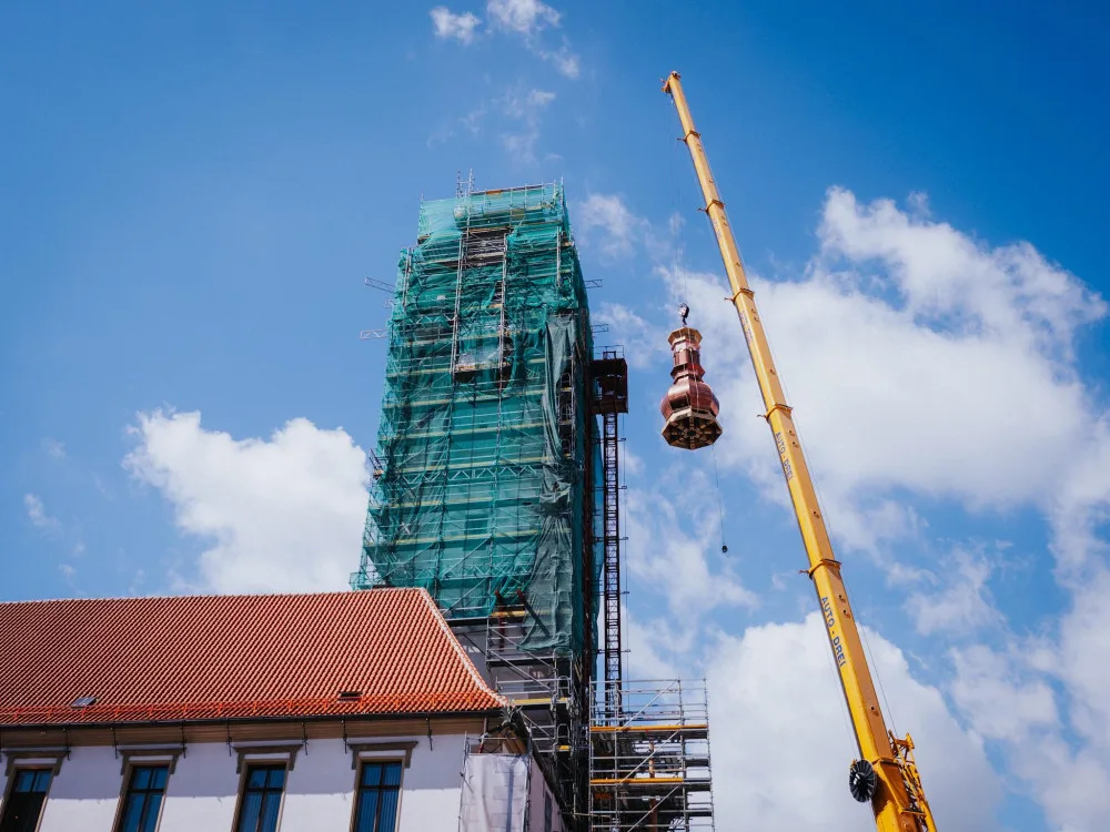 FOTO/VIDEO: Jeřáb dnes na olomouckou radnici vyzvedl prostřední část opravené věže