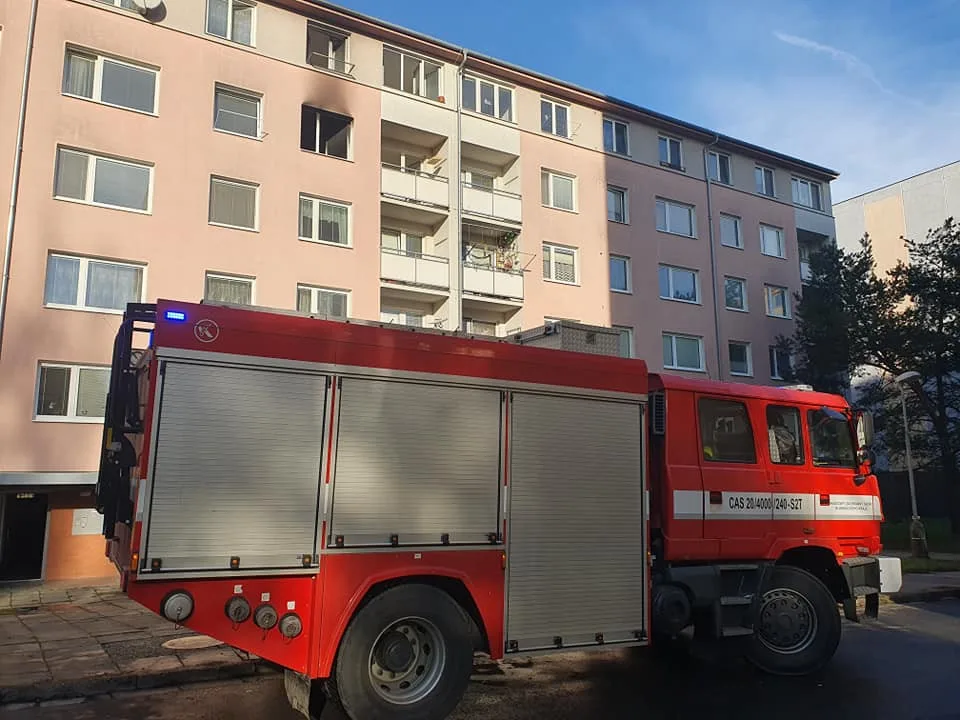 Požár v paneláku na Na Černé cestě. Hasiči z hořícího bytu zachránili jednu osobu, přiletěl pro ni vrtulník