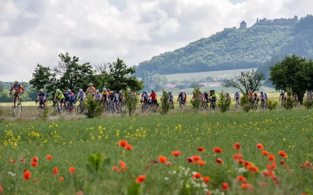 Velocipedista Josef Zimovčák s pelotonem cyklistů projíždí každoročně republikou pro nadační fond Na kole dětem. V pozadí hrad Helfštýn
