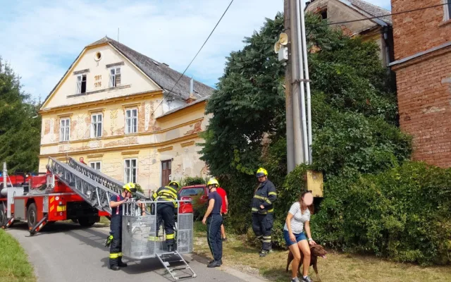 Operace labrador. Z římsy domu v Troubelicích hasiči sundávali psa, který zřejmě pronásledoval kočku