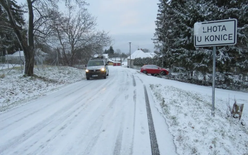 Mladá řidička jela na zasněžené silnici příliš rychle. Se svým autem dostala smyk a skončila v oplocení