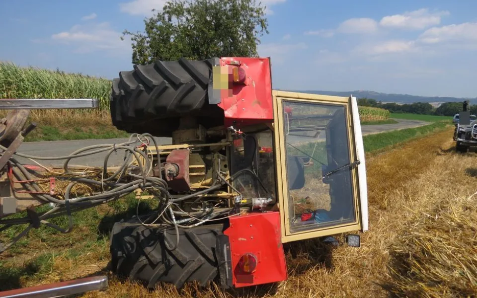 Traktorista jel příliš blízko krajnice, se strojem i s převáženou slámou skončil převrácený mimo silnici
